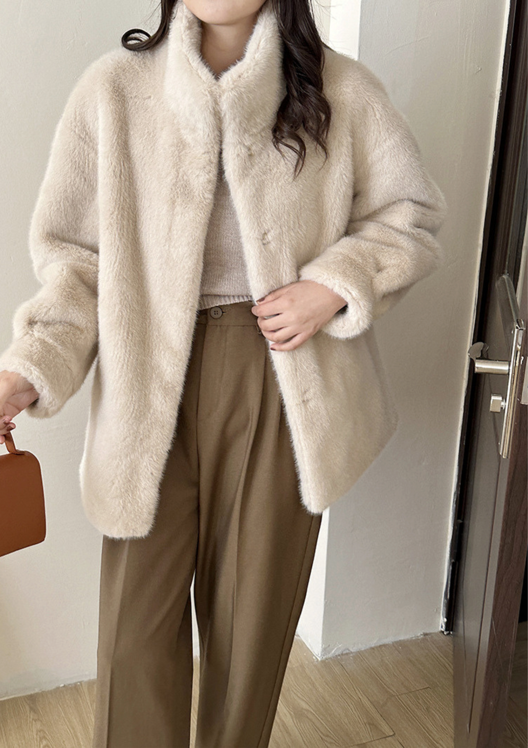lily Mila plush mink fur coat in cream with a stand collar, worn over a knit top and brown tailored trousers.
