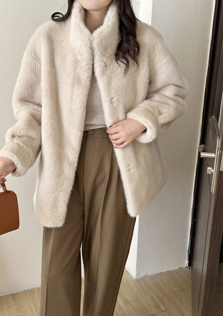 lily Mila plush mink fur coat in cream with a stand collar, worn over a knit top and brown tailored trousers.